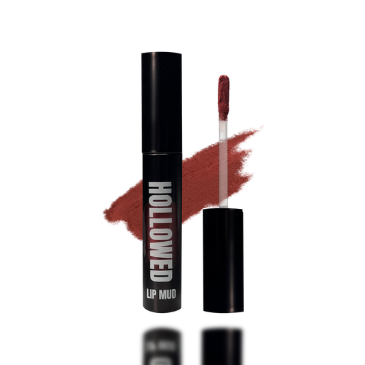 LIP MUD IN BLACK PACKAGING WITH A WINDOW TO SEE COLOR AND NEXT TO THE PRODUCT'S WAND. COLOR SWATCH BEHIND PRODUCT OF A MEDIUM REDDISH PINK COLOR