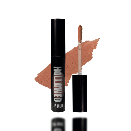 LIP MUD IN BLACK PACKAGING WITH A WINDOW TO SEE COLOR AND NEXT TO THE PRODUCT'S WAND. COLOR SWATCH BEHIND PRODUCT OF A PALE PEACH NUDE COLOR.